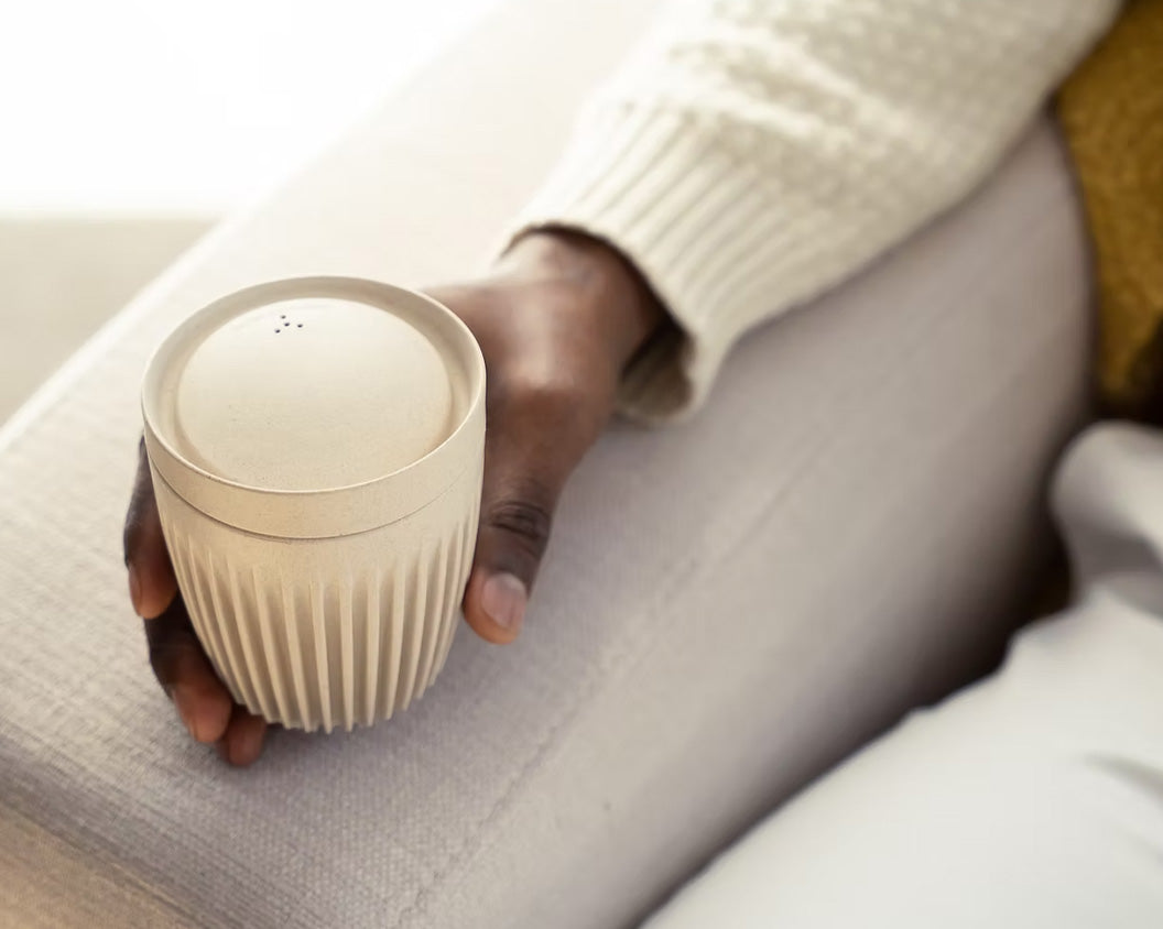 Person holding Natural Original HuskeeCup sitting on a sofa