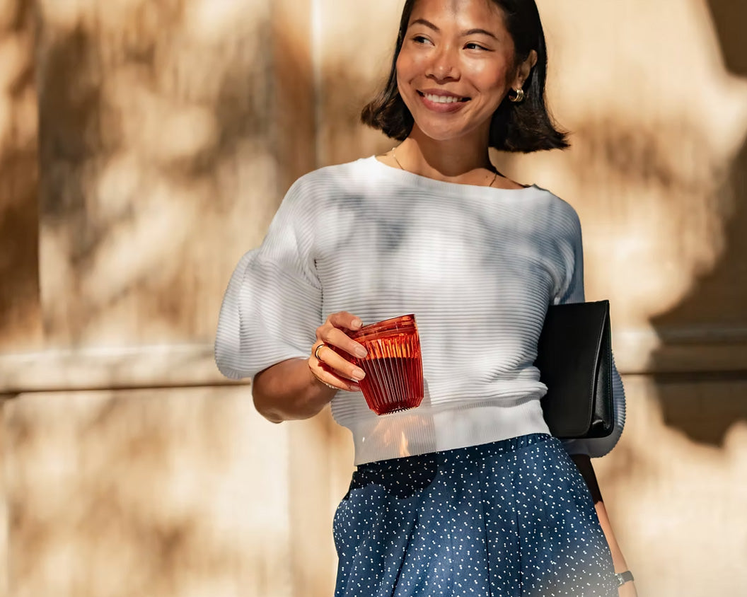 Woman smiling and holding HuskeeRenew amber with lid outside