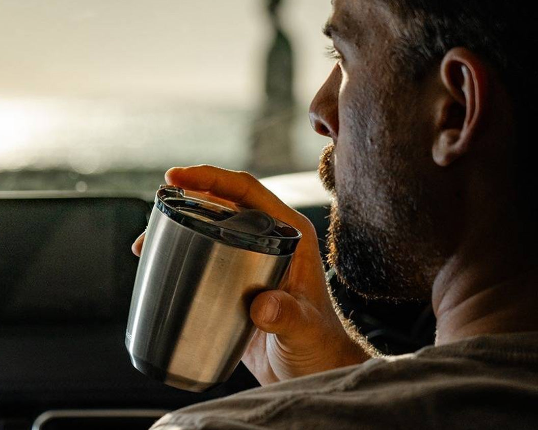 Man holding a brushed steel HuskeeSteel insulated coffee cup in a car
